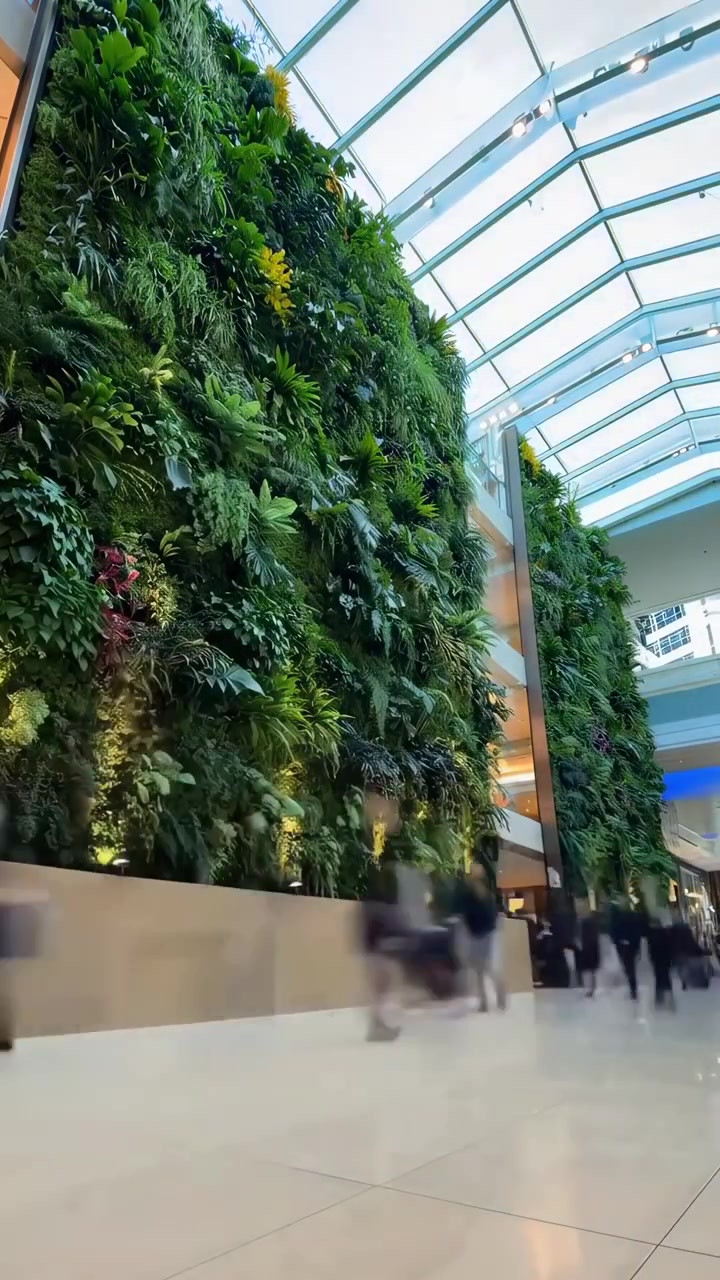 Pessoas Passando por um Grande Jardim Vertical em um Átrio Moderno