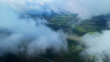 a smooth aerial shot view of a wind shear that partially covers a green landscape