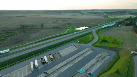 high-angle aerial view of highway stretching across vast open fields with vehicles, showcasing a rural landscape at sunset