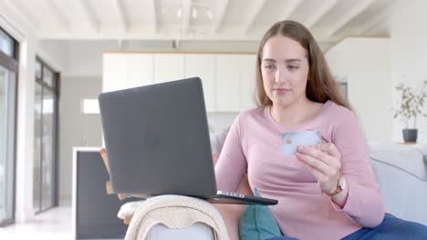 Happy-caucasian-woman-using-laptop-and-holding-credit-card-in-slow-motion