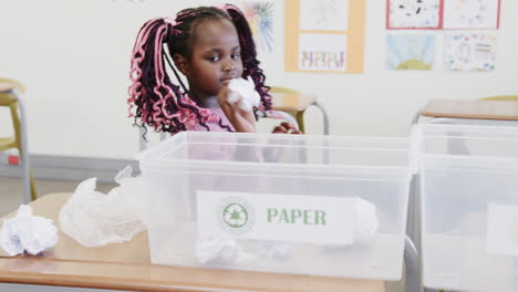 in school, young girl sitting near recycling bin, learning about sustainability