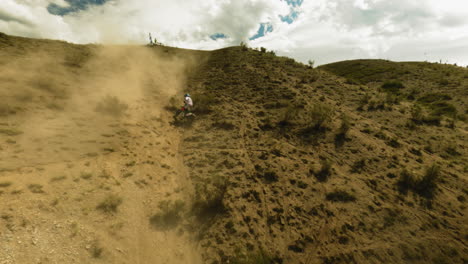 motorcyclist moves downhill slipping on dust fpv drone. sportsman handles with motorbike problems during racing at desert highland. road accident