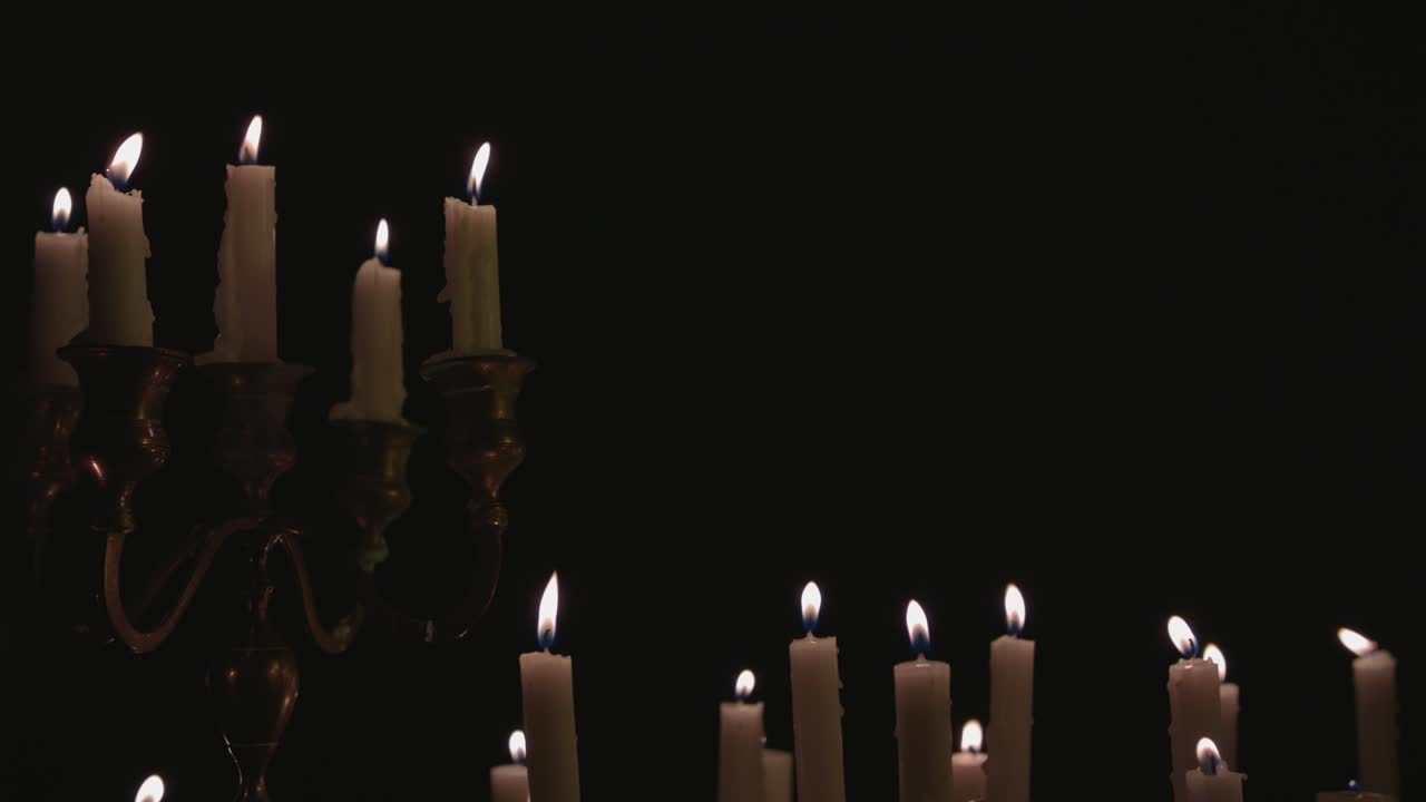 un grupo de velas blancas, algunas en un candelabro, encendidas y funcionando durante un tiempo
