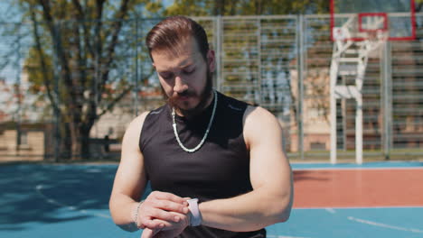 athletic sport man jogger use smart watch checking heart rate route for running on basketball court