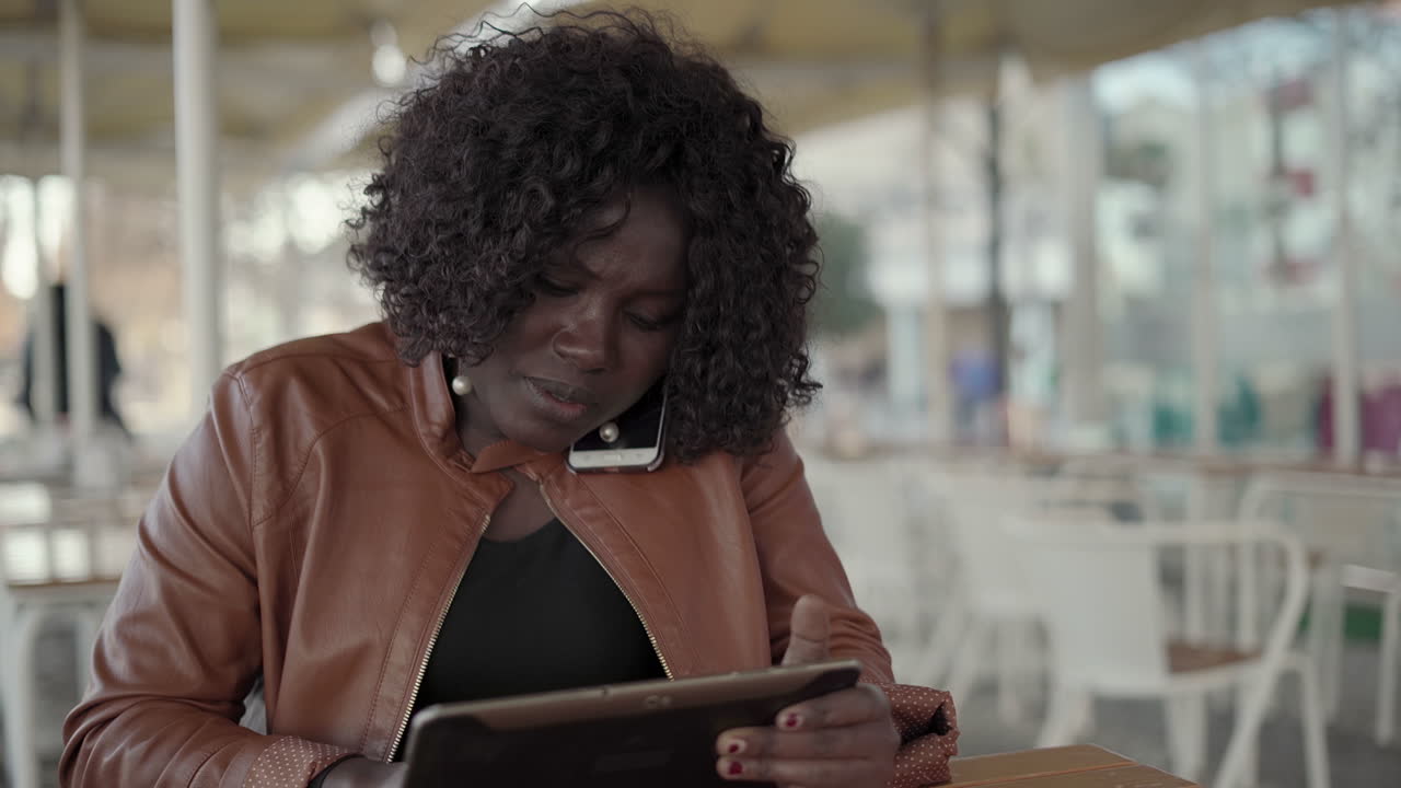 Focused female freelancer using smartphone and tablet pc