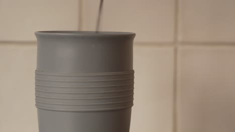 vista estática de café recién hecho que se vierte en una taza de café gris en la cocina