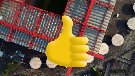 composición digital de pulgares hacia arriba icono contra vista aérea de almacén en la ciudad
