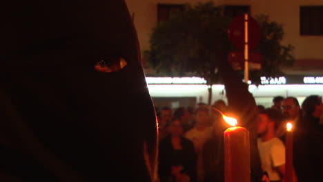 religious procession at night with masked participants and candles