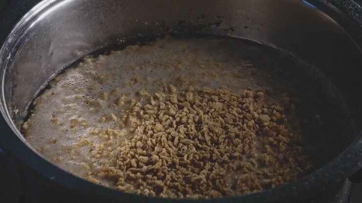 Aggiungere proteine vegetali testurizzate a una pentola piena di acqua bollente, vista ravvicinata.