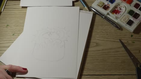 de arriba hacia abajo, cerca de manos femeninas dibujando una tarjeta de navidad y preparándose para pintar