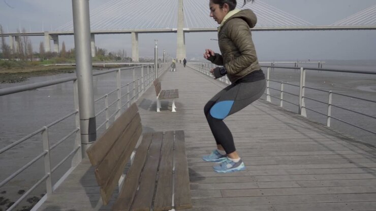 Side view of concentrated hindu woman jumping near wooden bench