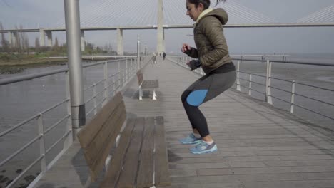 Side-view-of-concentrated-hindu-woman-jumping-near-wooden-bench