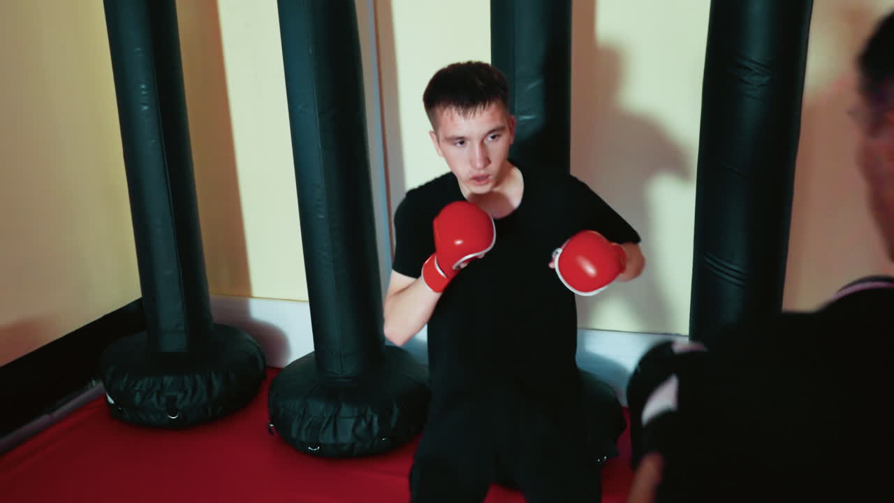 Fighters engaged in sparring session inside boxing gym, young men wearing gloves preparing for strikes with focused stances, training in combat techniques,discipline, and martial arts practice