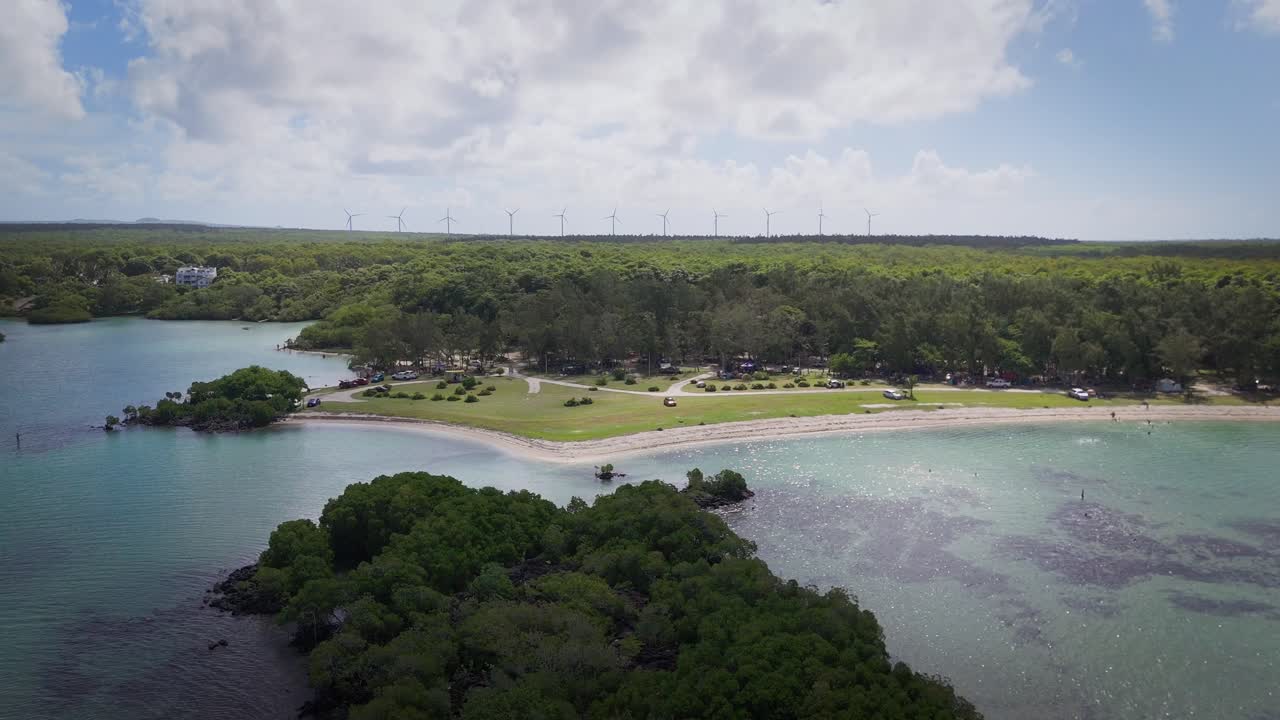 Aerial view of a serene beach and coastline with distant wind turbines in Mauritius, blending nature and renewable energy. Perfect for travel, eco-tourism, and sustainability concepts.