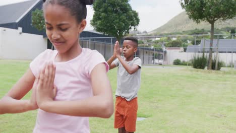 video de una colegiala y un colegial diversos practicando meditación de yoga en una clase al aire libre, espacio de copia