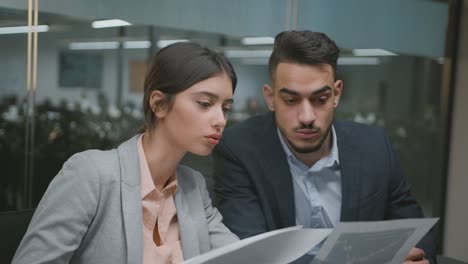 business analytics concept. young professional multiethnic coworkers reading financial reports and graphs at office