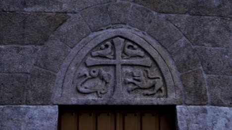 carved stone detail of cross and snake lion and fish animals in old church