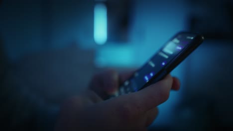 detail of hands holding phone and texting at night