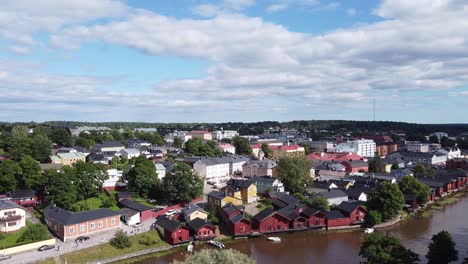 aerial view showing wooden red houses on river shore and beautiful landscape in background