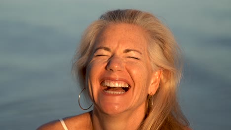 beautifully lit mature blonde woman wearing granny glasses and looking silly with ocean behind her