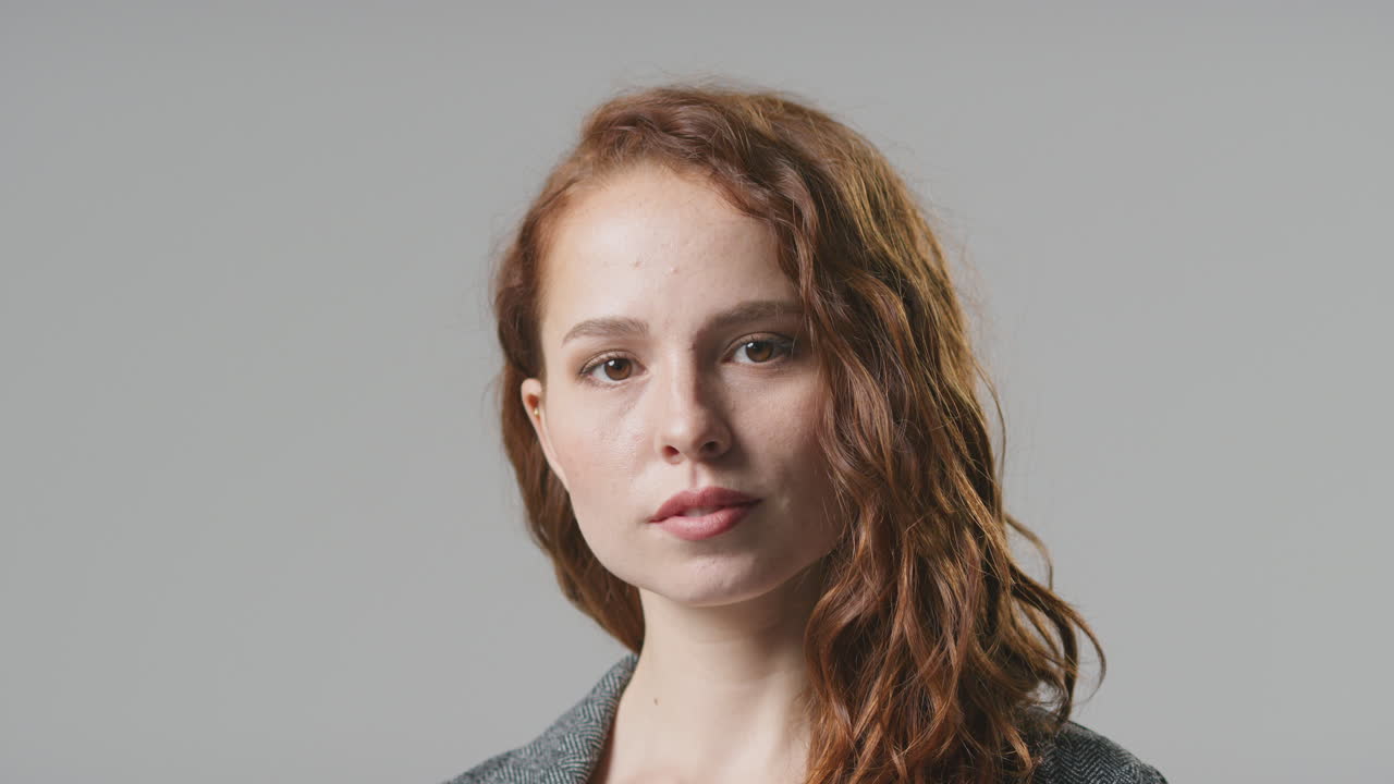 retrato de estudio de cabeza y hombros de una joven mujer de negocios seria contra un fondo plano