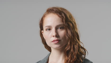 Head-And-Shoulders-Studio-Portrait-Of-Serious-Young-Businesswoman-Against-Plain-Background