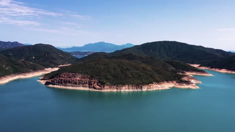 Paralaje-Aéreo-Del-Agua-Turquesa-Del-Embalse-De-La-Isla-Alta,-Colinas-Verdes-Y-Columnas-De-Roca-Hexagonal,-Península-De-San-Kung-En-Hong-Kong,-China