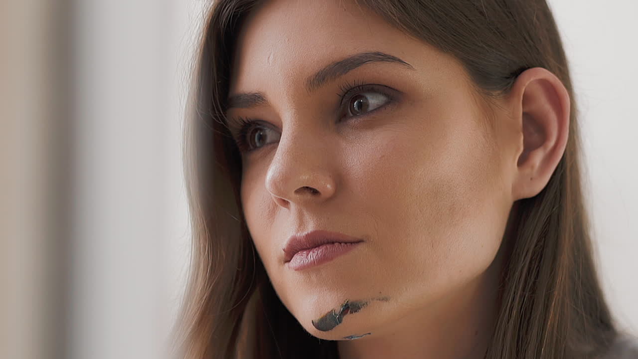 красивая женщина-художник с серой краской на подбородке в студии