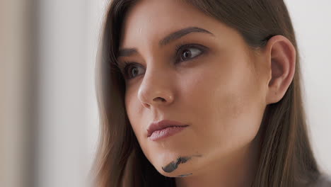 pretty woman artist with grey paint smear on chin in studio