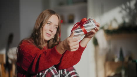 feliz mujer hermosa girando envuelto regalo de navidad en casa