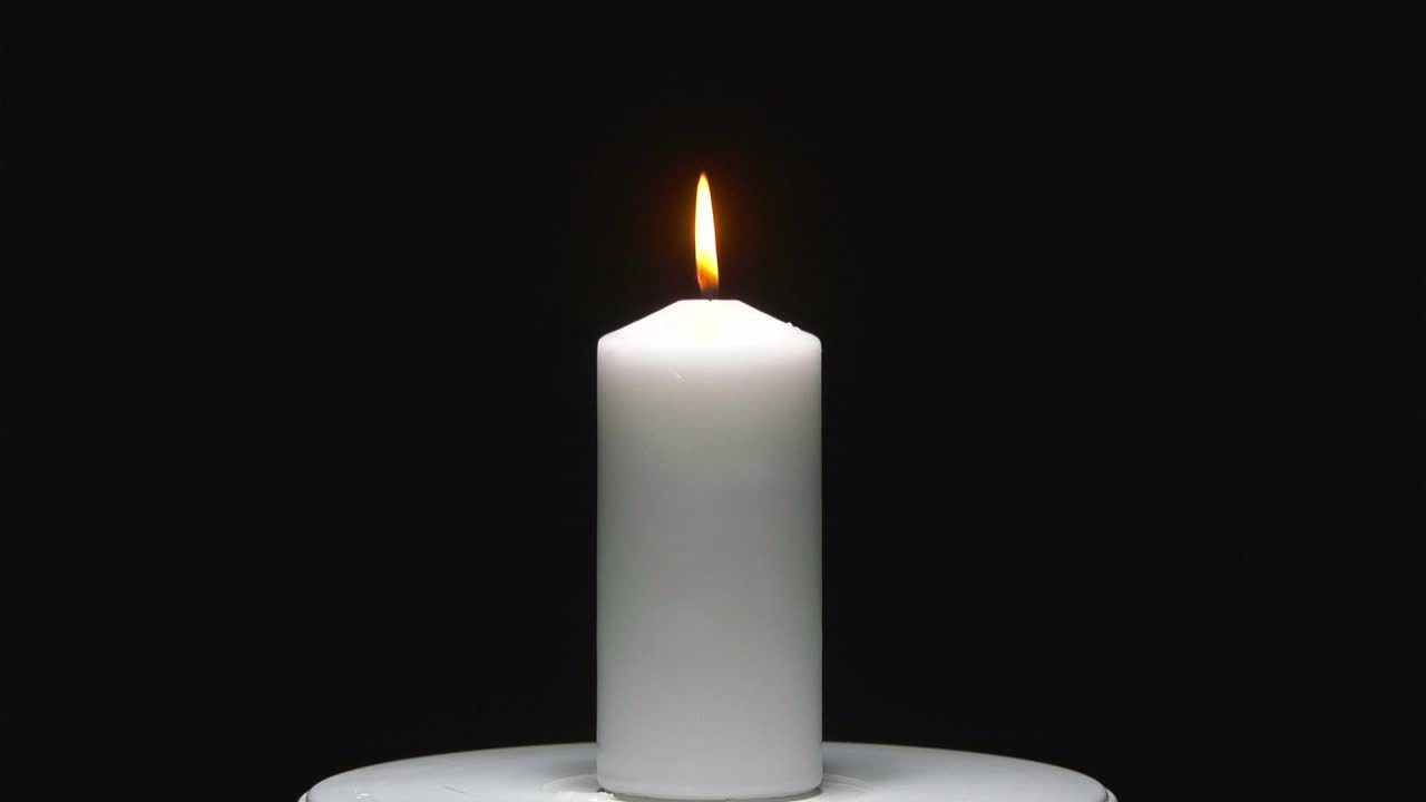 Klidný plamen svíčky na černém pozadí, ideální pro klíčování.