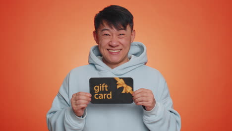 handsome man showing pointing on gift discount certificate voucher coupon for store holidays sale