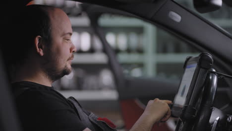 de cerca: utilizando una tableta digital para un diagnóstico de automóviles. mecánico utilizando una tableta en el servicio de garaje de reparación. software de diagnóstico interactivo en una computadora avanzada.