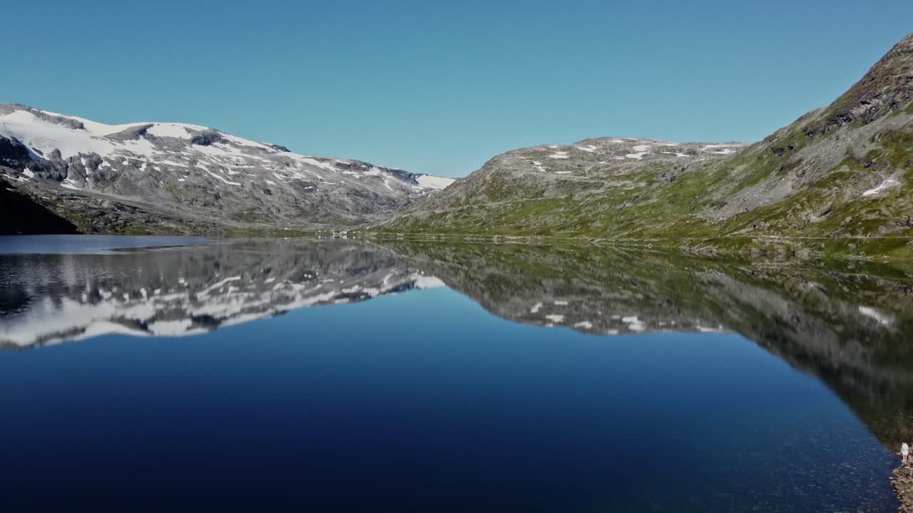 Lake in the Rauma Commune of Norway, with snow capped mountains in the background
