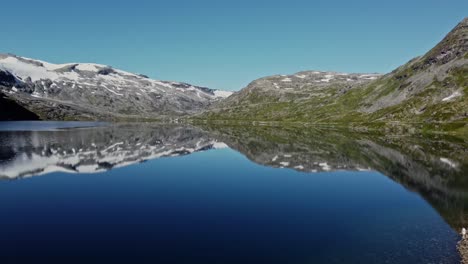 Lake-in-the-Rauma-Commune-of-Norway,-with-snow-capped-mountains-in-the-background