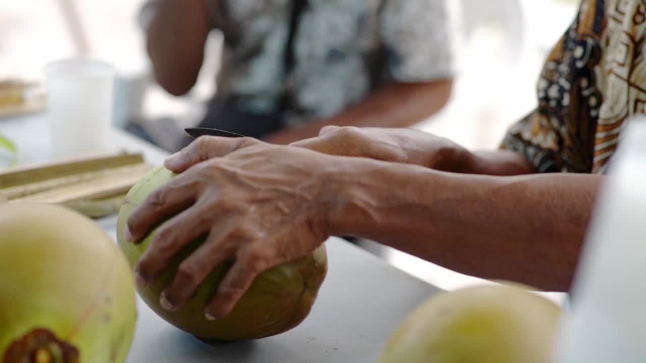Homem fazendo entalhe artístico em coco verde com faca pequena, close-up do corte
