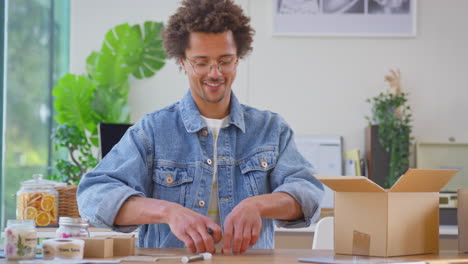 Hombre-Que-Dirige-Un-Negocio-En-Línea-Desde-Casa-Empacando-Velas-Boutique-Para-Enviar-Etiquetas-De-Escritura