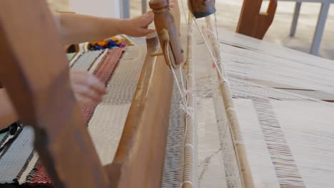 close-up of a traditional loom as a woman waves a rug