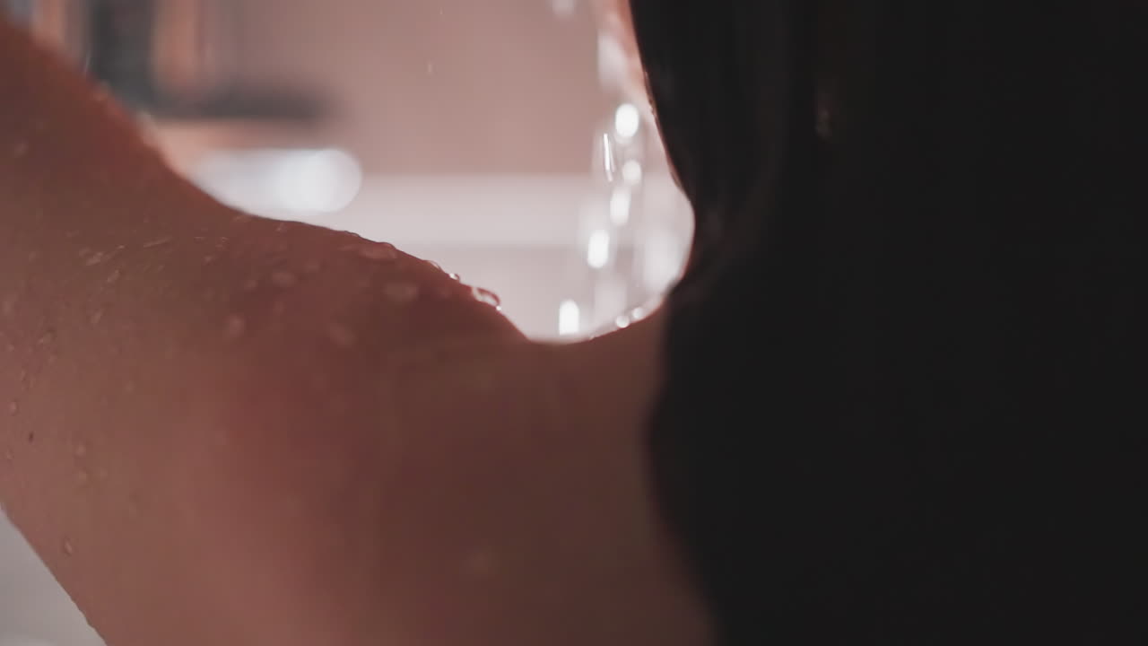 여자가 샤워실 안에 서서 물이 아지는 느낌을 느끼고, 여자가 물이 몸을 감싸도록 허용하고, 물방울의 따뜻함을 느끼고, 매일 머리카락을 는 의식을 느니다.