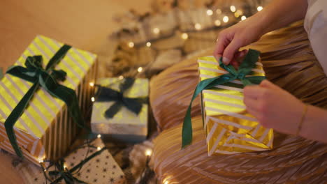 woman ties a ribbon on a present wrapping it