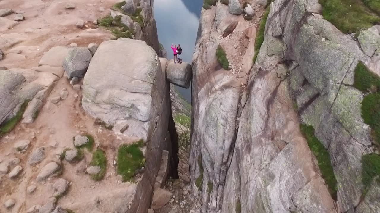 вид с воздуха показывает пару, стоящую на валуне кьерагболтен на горе кьераг в рогаланде (норвегия).