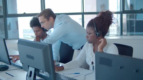 male manager helping call center operators with new software