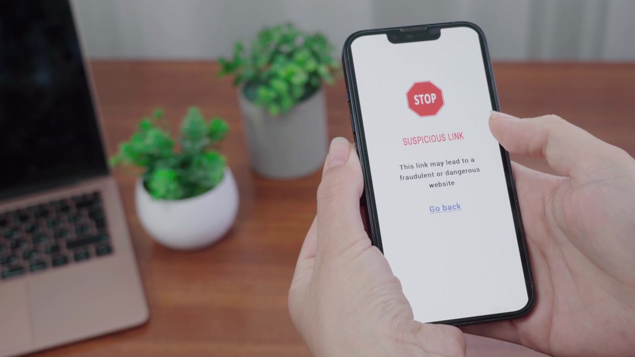 Un'app di informazioni AI mostra un avviso STOP per un link sospetto su uno schermo mobile mentre un pollice si avvicina all'opzione per tornare indietro