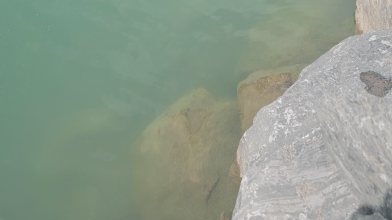 Close up, looking down at the rocky lake side of Emerald Lake with blue water in British Columbia, Canada