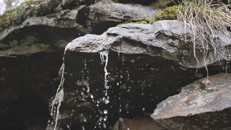 slow motion dolly move of water bunching up and sliding and falling down a rock