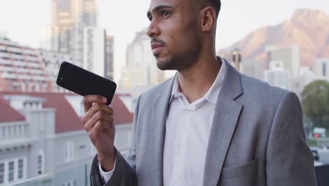 Video-of-biracial-businessman-talking-on-smartphone-on-office-balcony