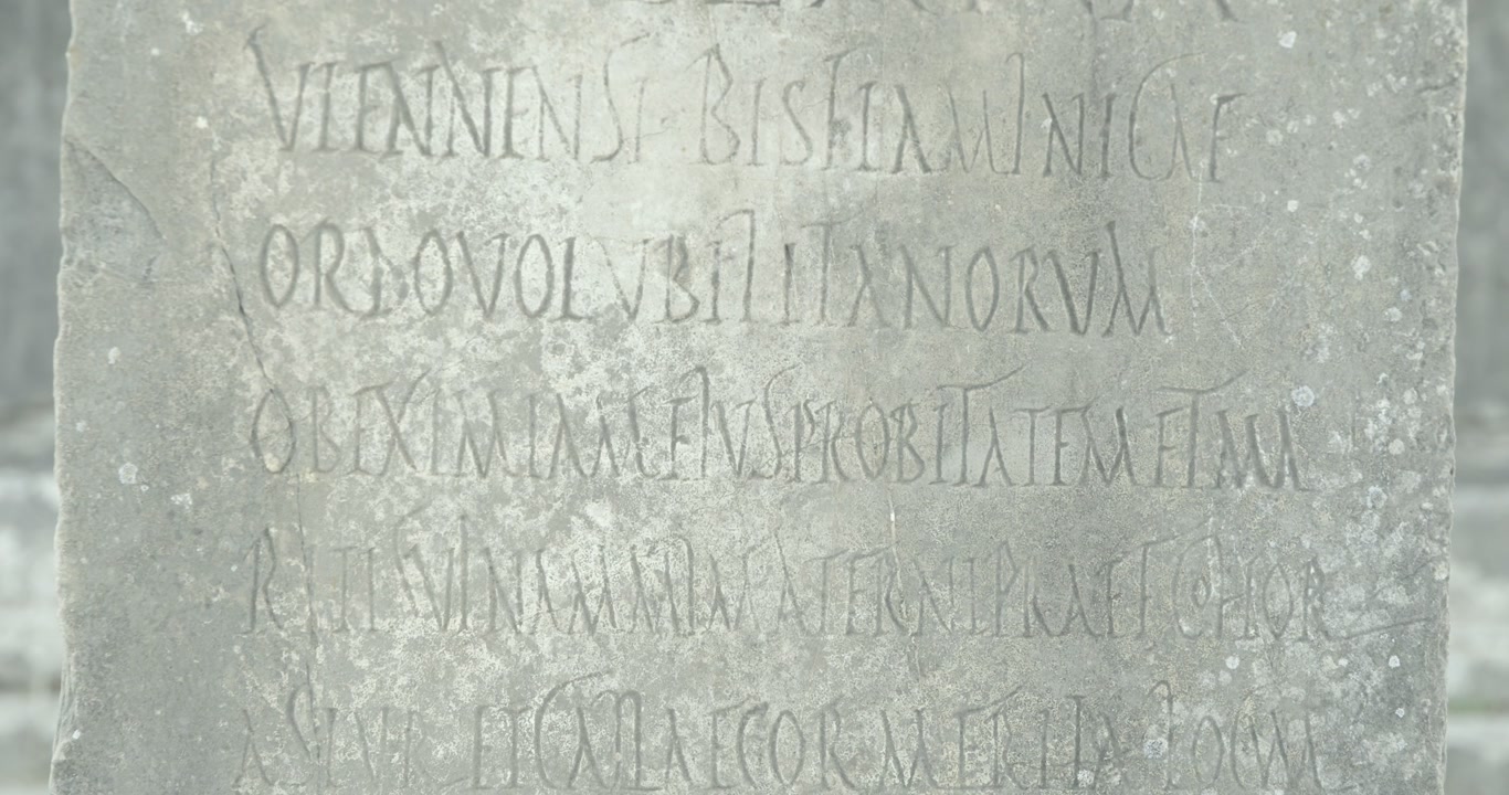 Close-up static view of a Latin inscription carved into stone at Volubilis, preserving Roman epigraphic evidence from Morocco's UNESCO World Heritage archaeological site.