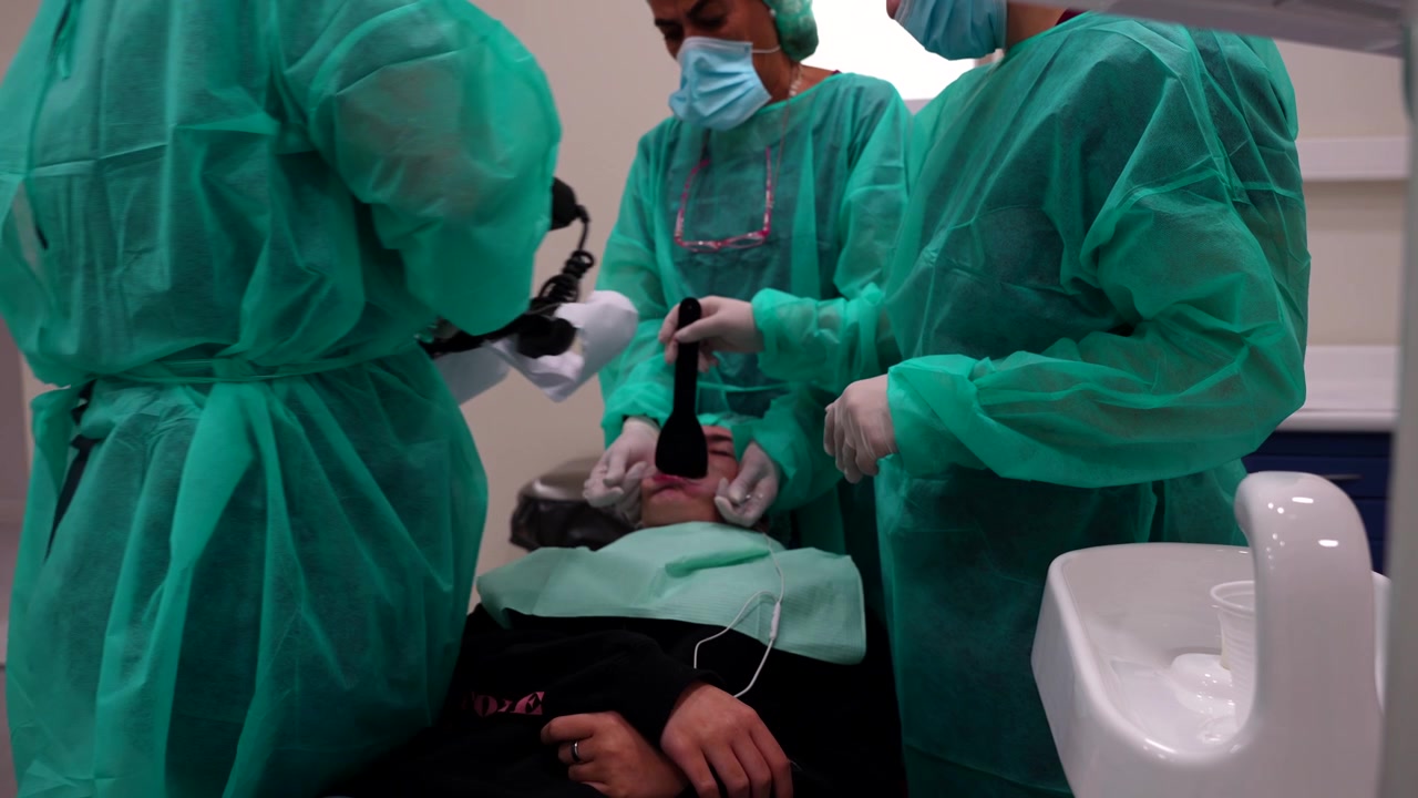 Un team di dentisti che fotografa la bocca del proprio paziente con una macchina fotografica