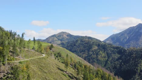 Antena-Acercándose-A-Una-Pequeña-Pista-En-Una-Colina-De-Montaña-Verde