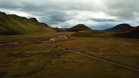 aerial landscape view over two cars speeding on a dirt road through icelandic highlands